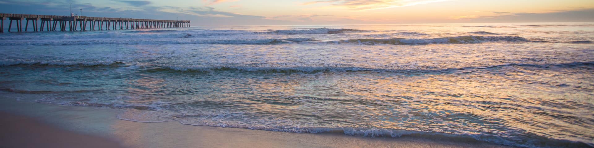 panama city beach florida ocean at shoreline with beautiul sunset clouds and pier into the water