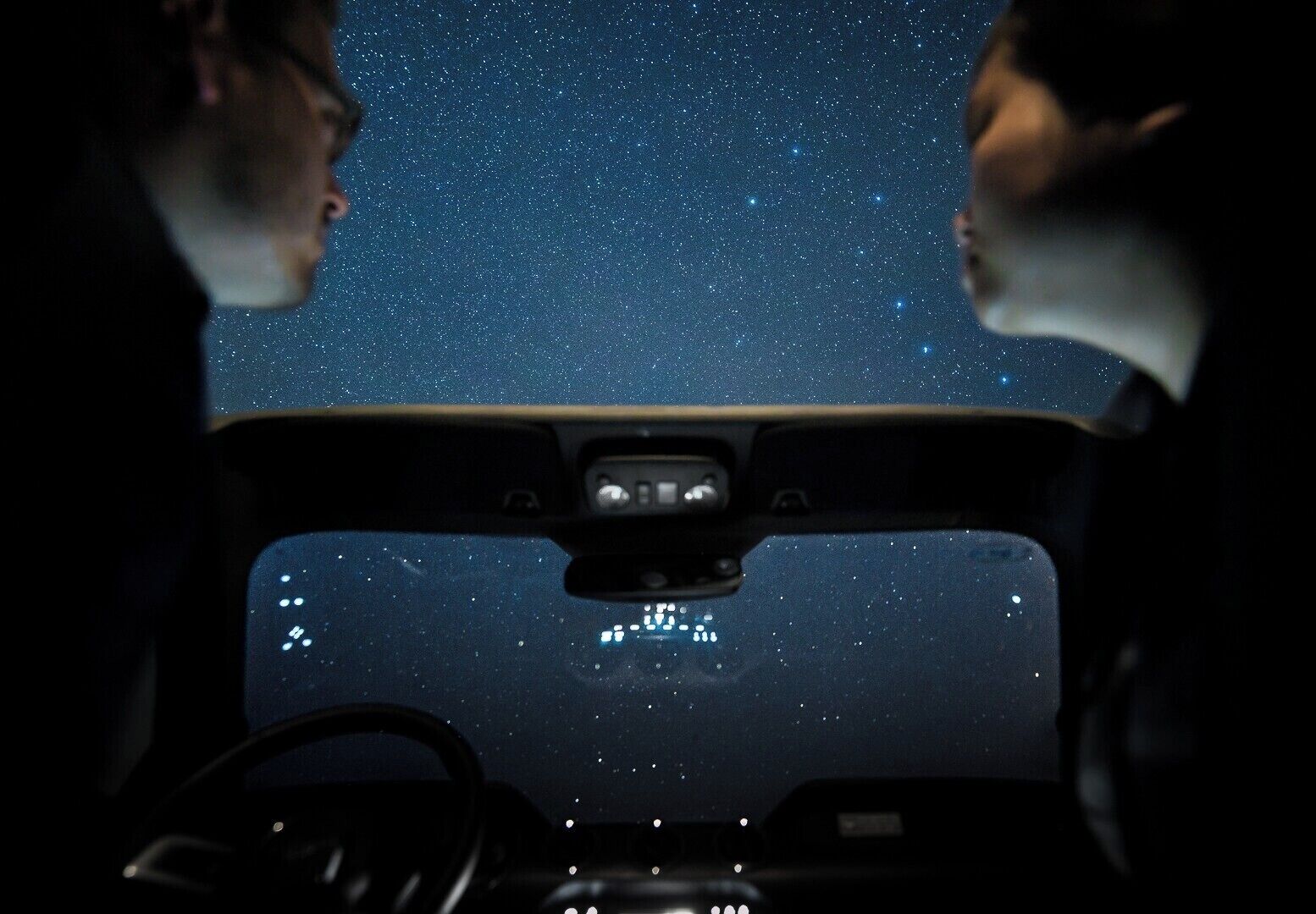 The interior of a car with a starry night sky visible through the windshield.