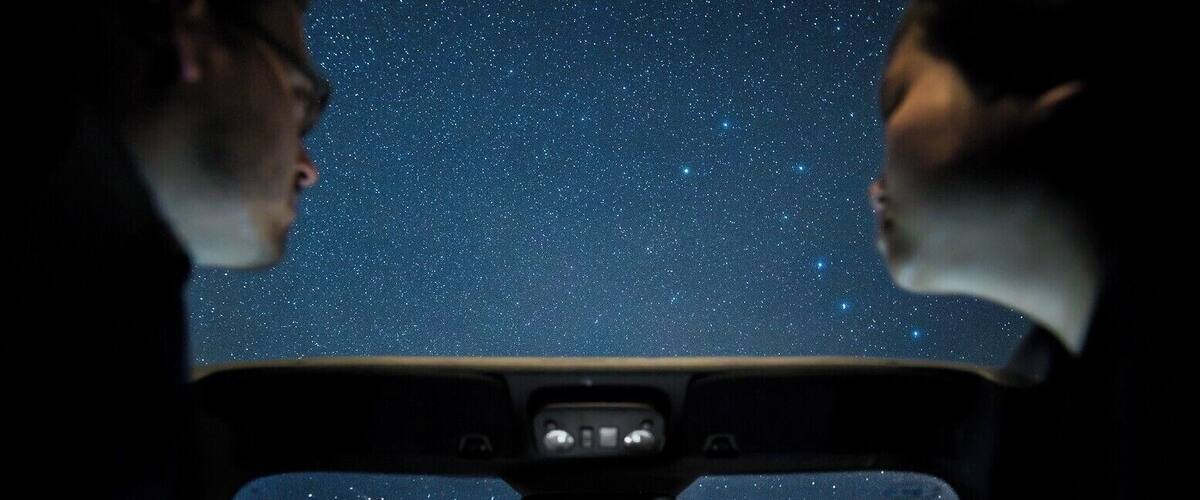 The interior of a car with a starry night sky visible through the windshield.