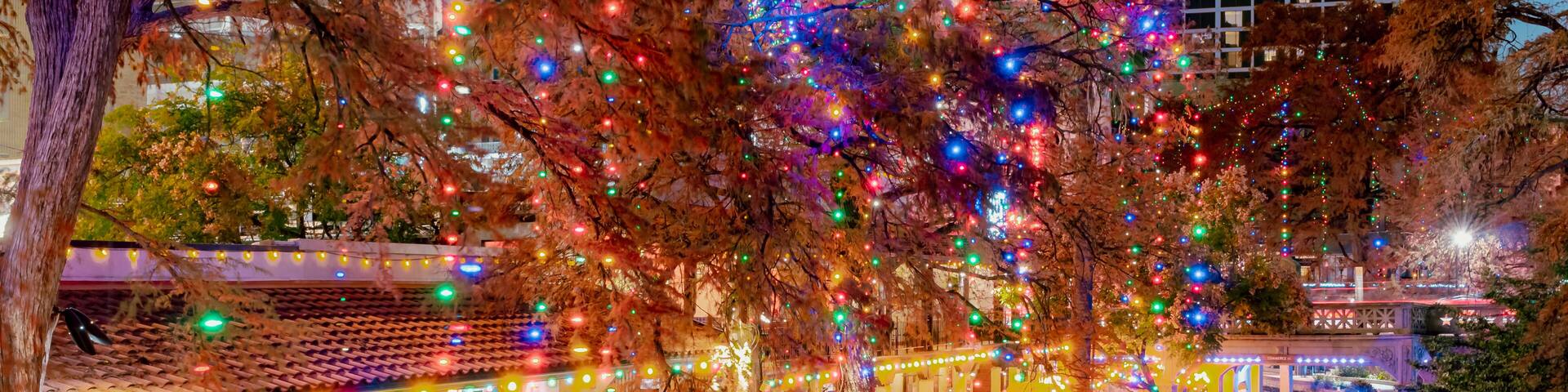 A riverside walkway adorned with colorful umbrellas and festive lights.