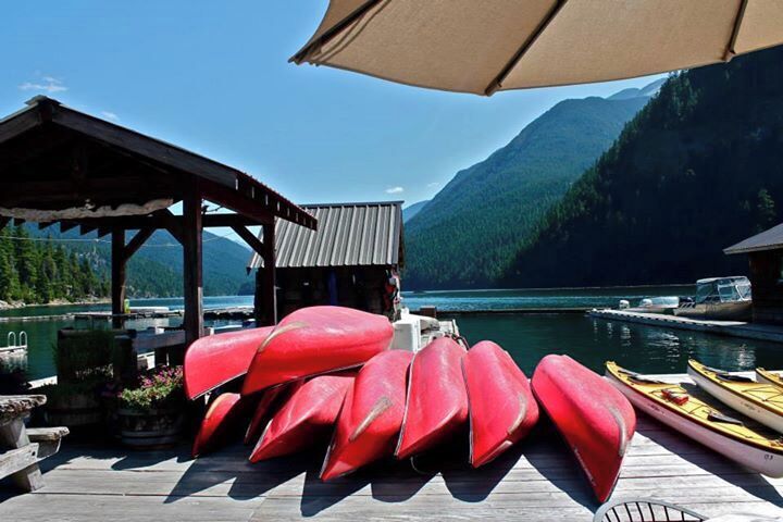 A dock with red kayaks and a small building.