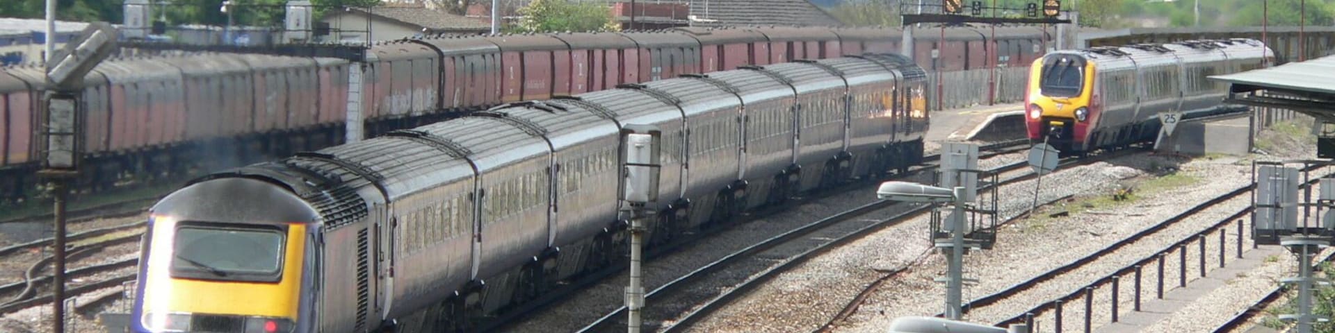 A westbound First Great Western HST enters Bristol Parkway railway station while a northbound Class 220 Virgin Voyager departs. This photograph was taken looking west from the bridge over the railway just off Hambrook Lane, Stoke Gifford about 1 third of a mile east of the station.