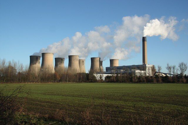 A power plant with cooling towers and a smokestack emitting steam.