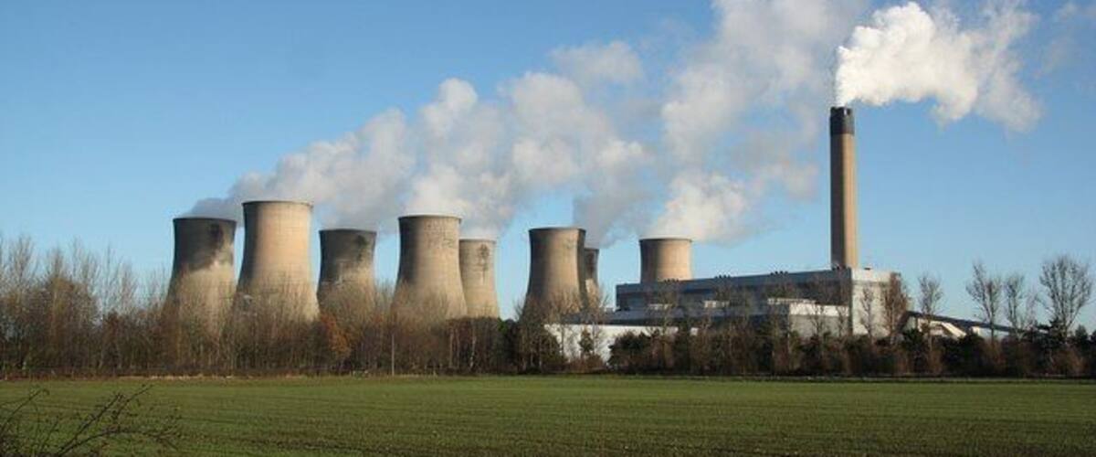 A power plant with cooling towers and a smokestack emitting steam.