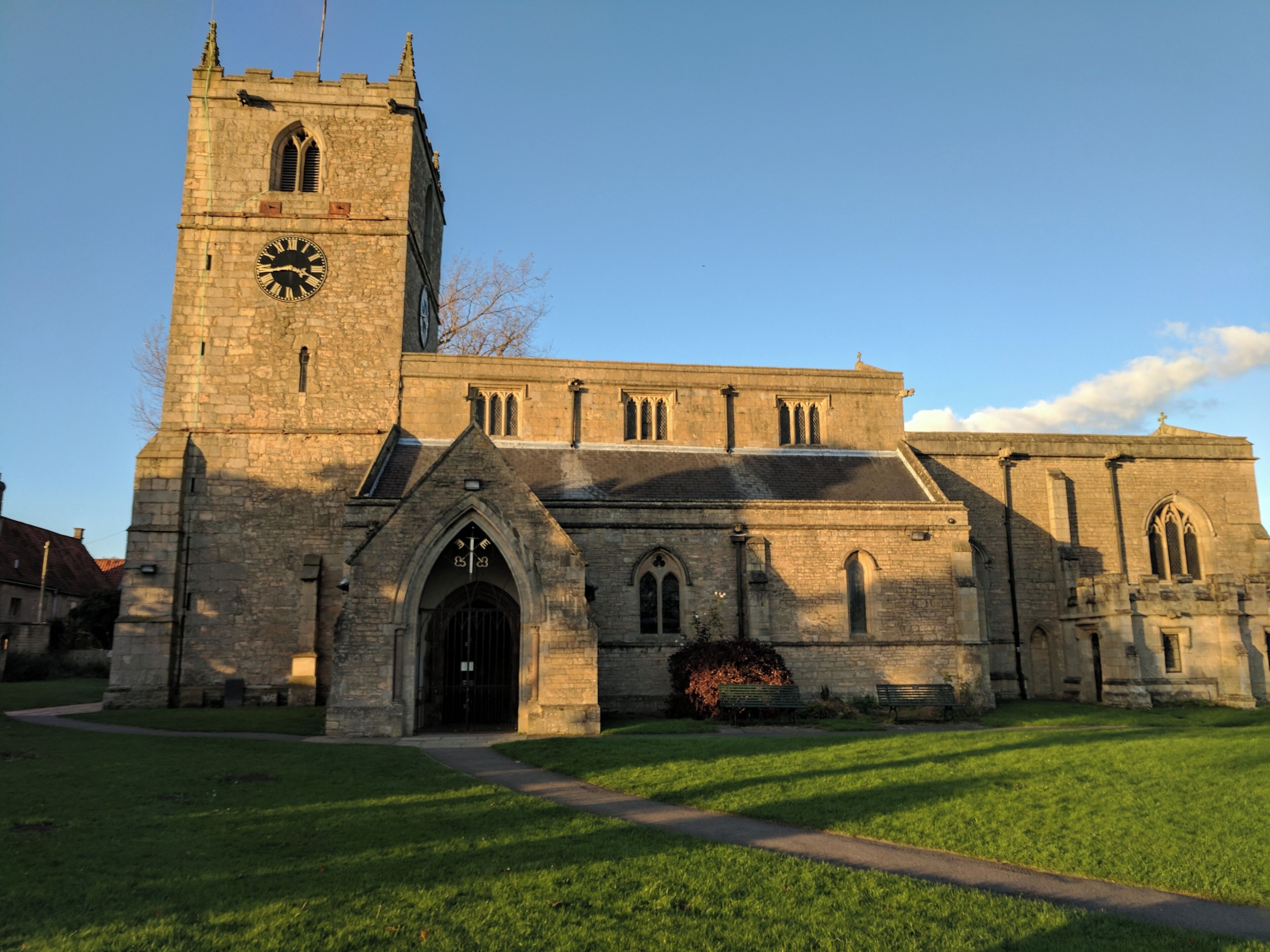 A historic church with a clock tower, arched windows, and a well-maintained lawn.