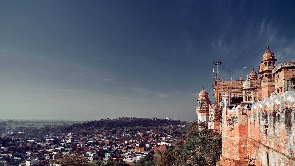 A historic fort with domed towers overlooking a densely populated town.