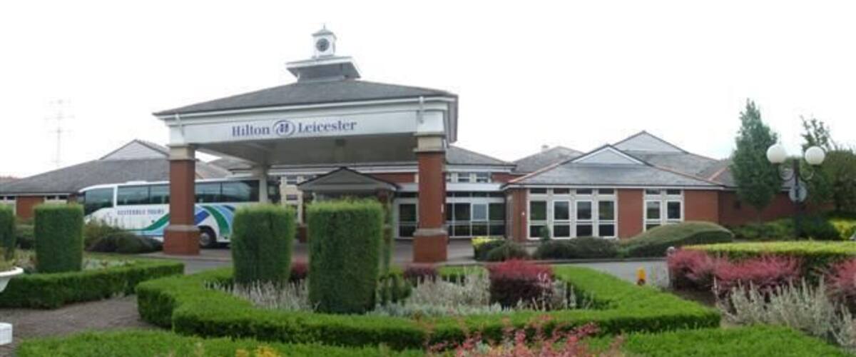 A Hilton Leicester hotel with a well-maintained garden and a parking area.