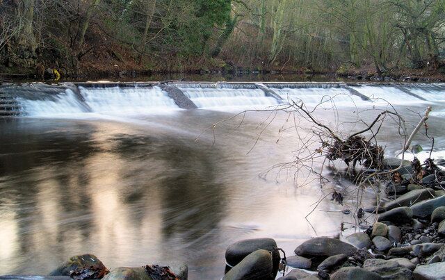 A waterfall with a rocky foreground and trees in the background.
