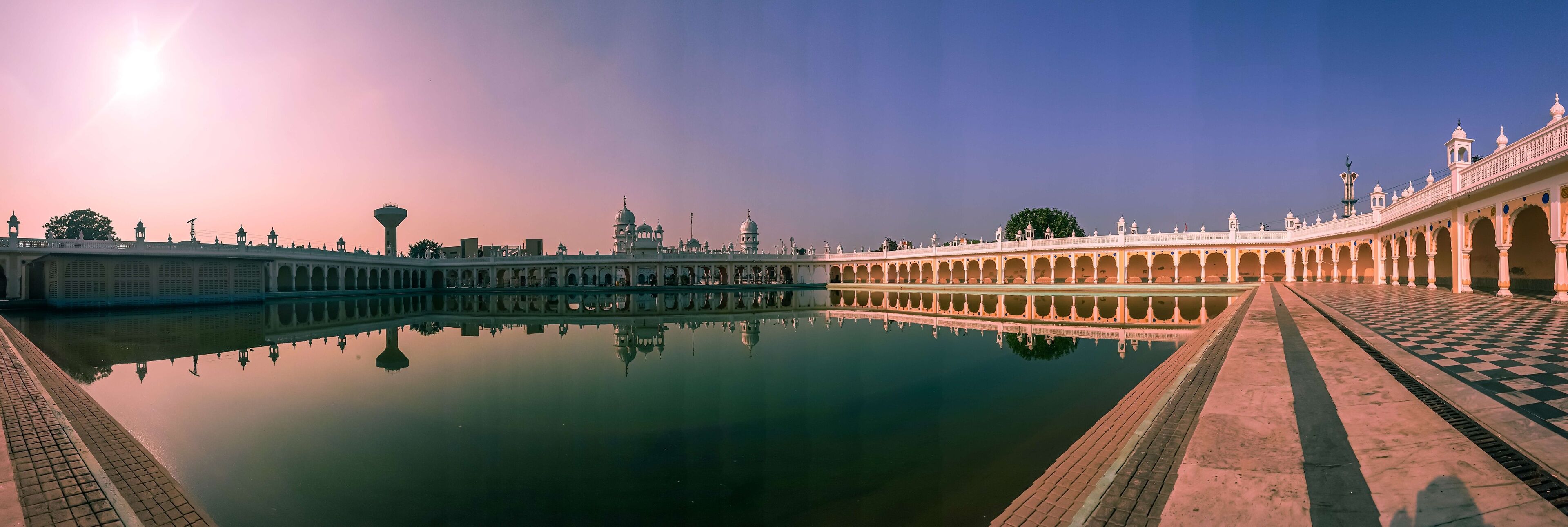 A grand palace with a reflective water body, ornate architecture, and a clear sky.