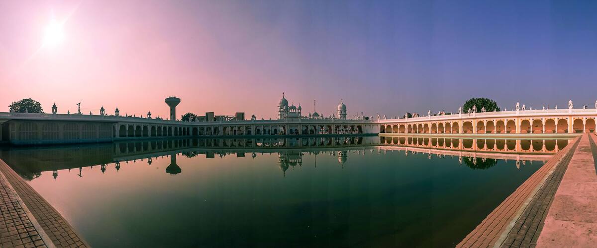 A grand palace with a reflective water body, ornate architecture, and a clear sky.