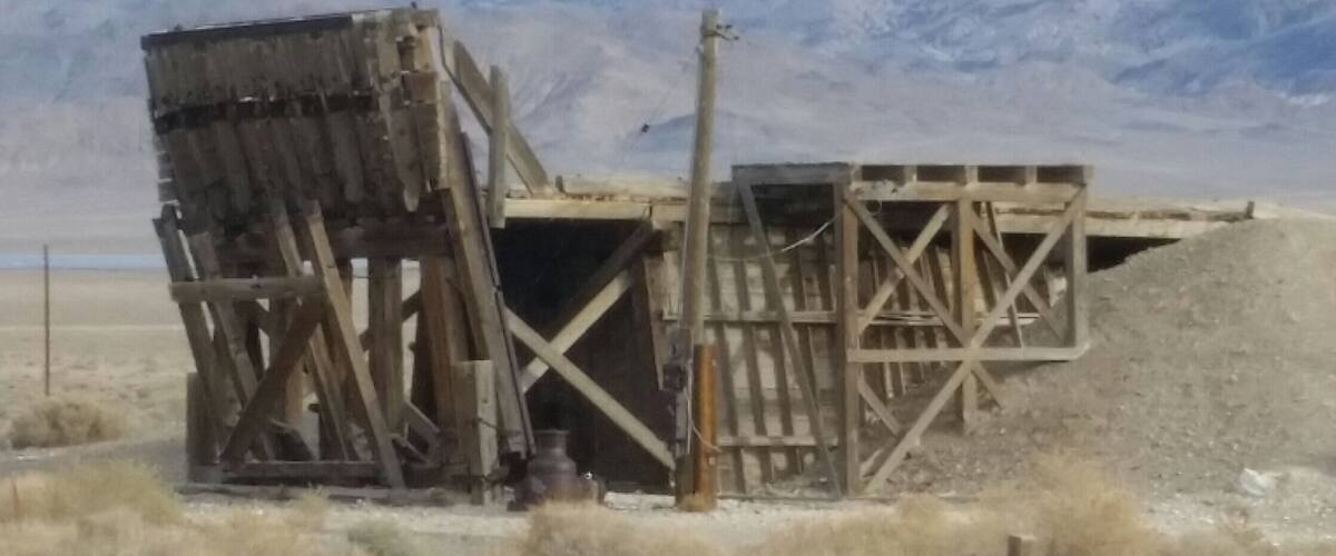 A wooden structure in a desert with mountains in the background.