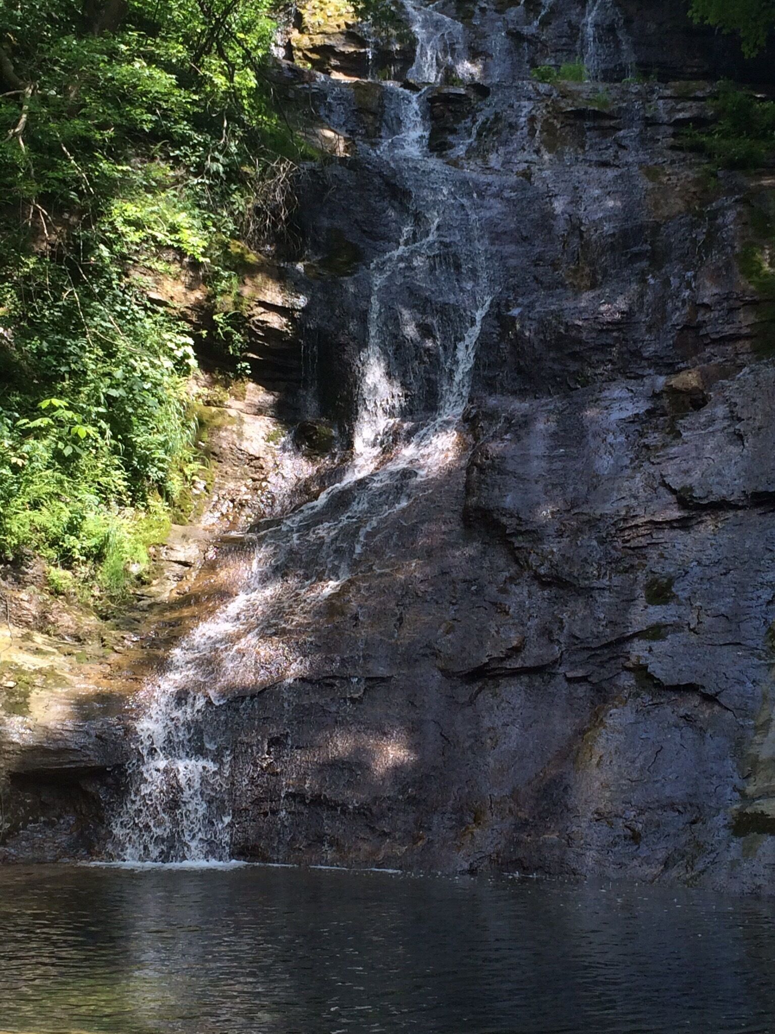 A waterfall cascading over a rocky cliff surrounded by lush greenery.