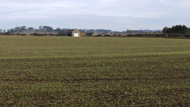 A vast agricultural field with a small building in the distance.