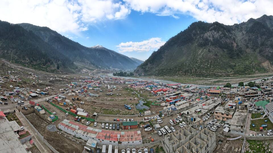 A mountainous town with a river, buildings, and a prominent red-roofed structure.