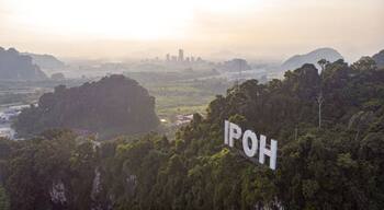 Paisagem com uma grande formação rochosa e o texto 'IPOH' em primeiro plano.