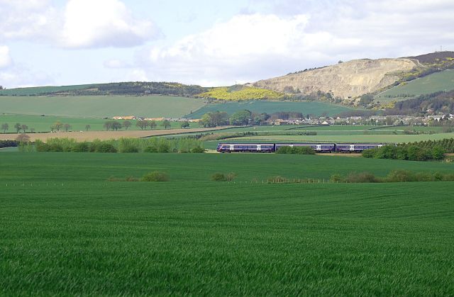 By Seggie Looking towards Balmullo and Lucklaw with its Redstone quarry. The Edinburgh bound train is picking up speed having just left Leuchars.