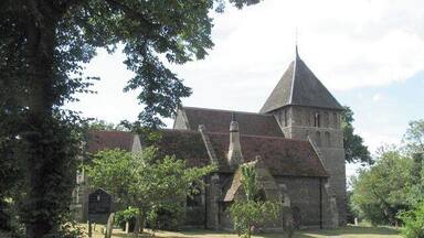 A historic church with a prominent tower and a well-maintained garden.