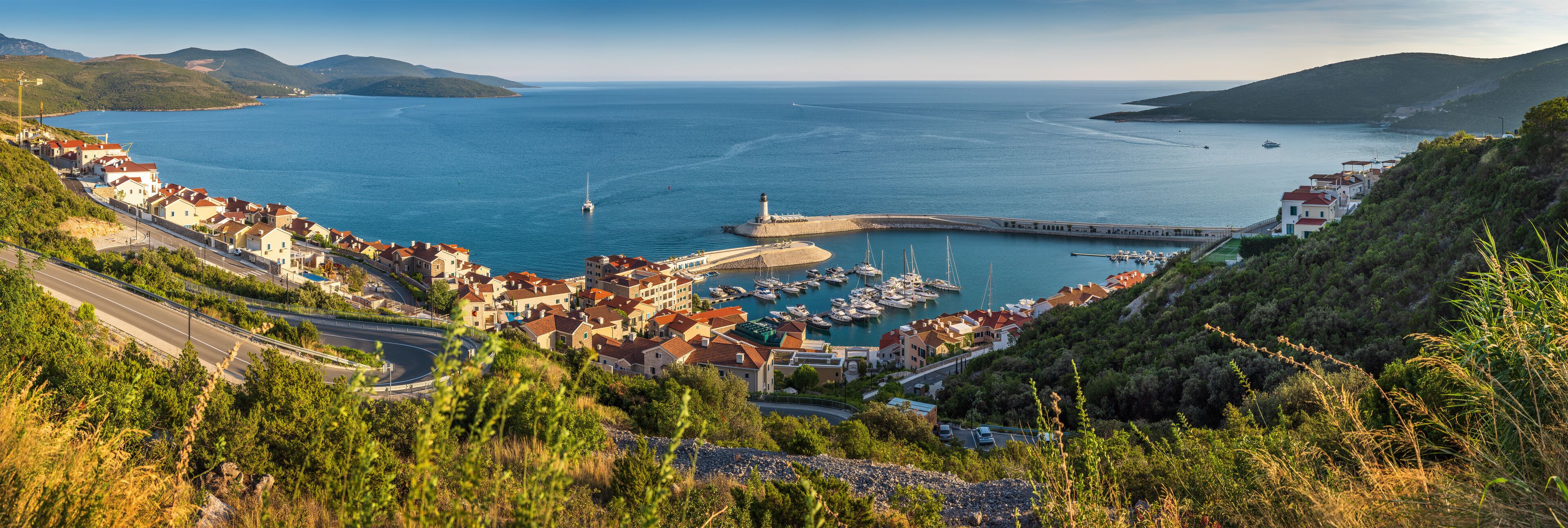 A coastal town with a marina, boats, and a lighthouse.