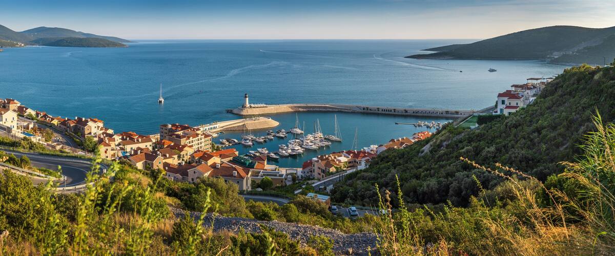 A coastal town with a marina, boats, and a lighthouse.