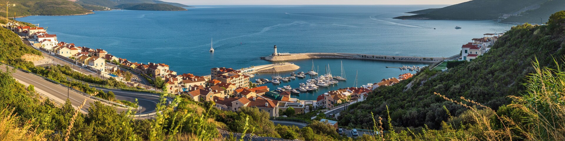 A coastal town with a marina, boats, and a lighthouse.