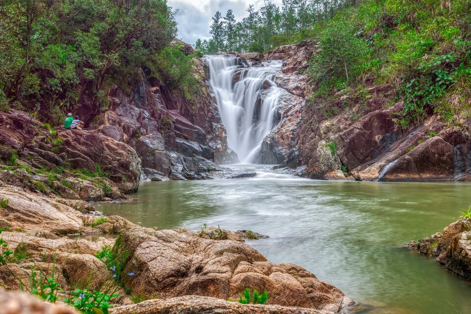 A waterfall surrounded by rocky terrain and greenery.