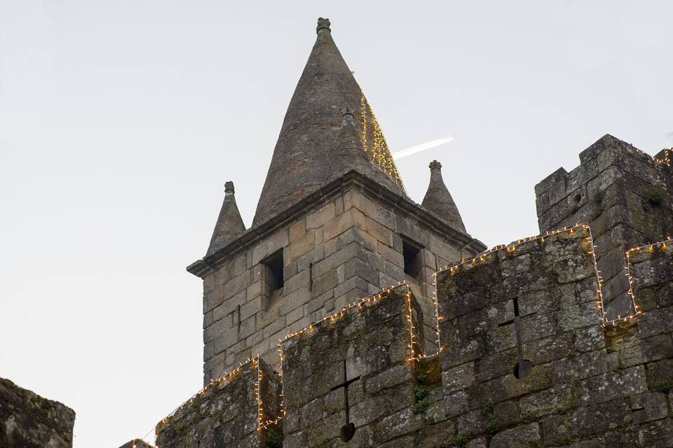 Uma torre de pedra com telhado pontiagudo e uma cruz na parede.