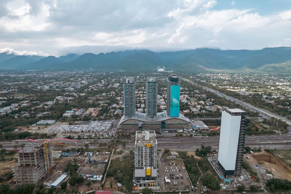 Une vue aérienne d’une ville avec deux gratte-ciel imposants, une mosquée et les montagnes environnantes.