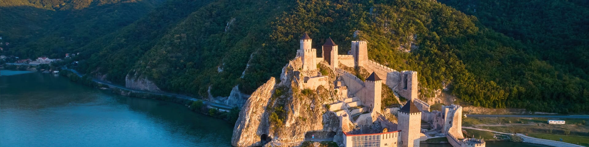 The medieval fortress of Golubac against iron gate of national park Djerdap, mirroring in the waters of the Danube. Colorful sunset light, blue sky. Aerial shot. Famous tourist place, Serbia.