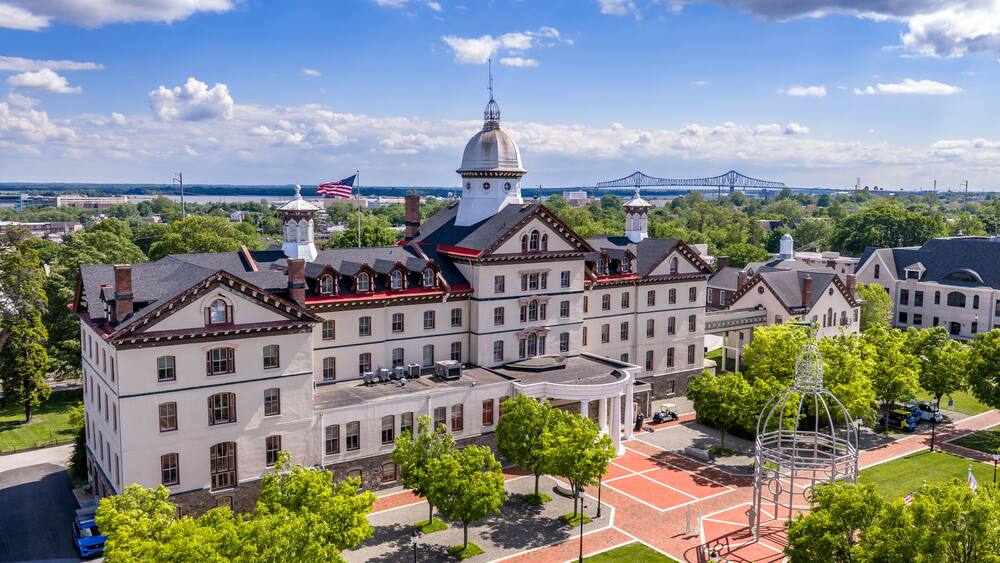 A historic building with a dome, a bridge in the background, and a red brick courtyard.