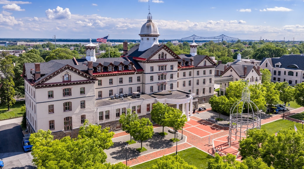A historic building with a dome, a bridge in the background, and a red brick courtyard.