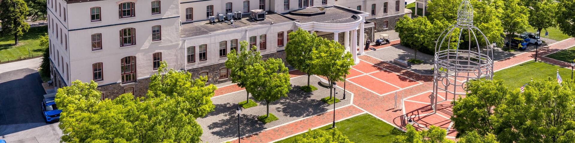 A historic building with a dome, a bridge in the background, and a red brick courtyard.