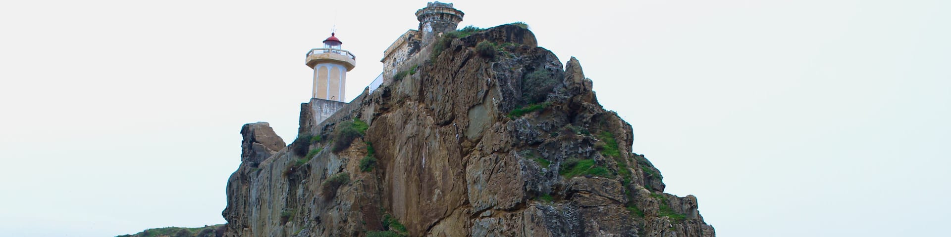 A lighthouse on a rocky cliff overlooking the sea.