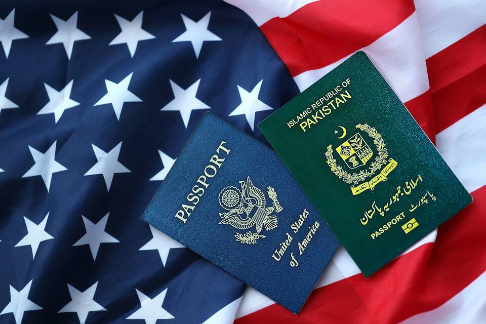 Two passports, one from the United States and one from Pakistan, placed on an American flag.