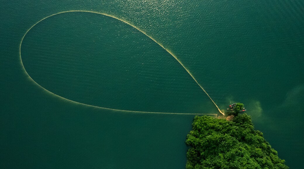 Une vue aérienne d’un lac où un bateau laisse derrière lui une large traînée.
