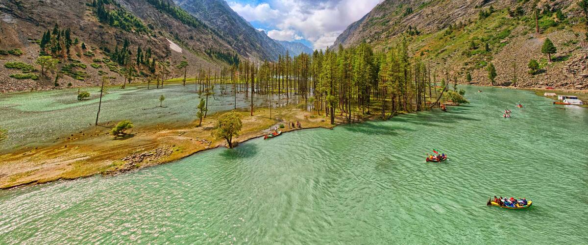 Un fiume circondato da montagne, con acque limpide e alcune imbarcazioni.