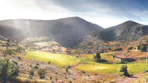 A mountainous landscape with a valley, scattered houses, and a clear sky.