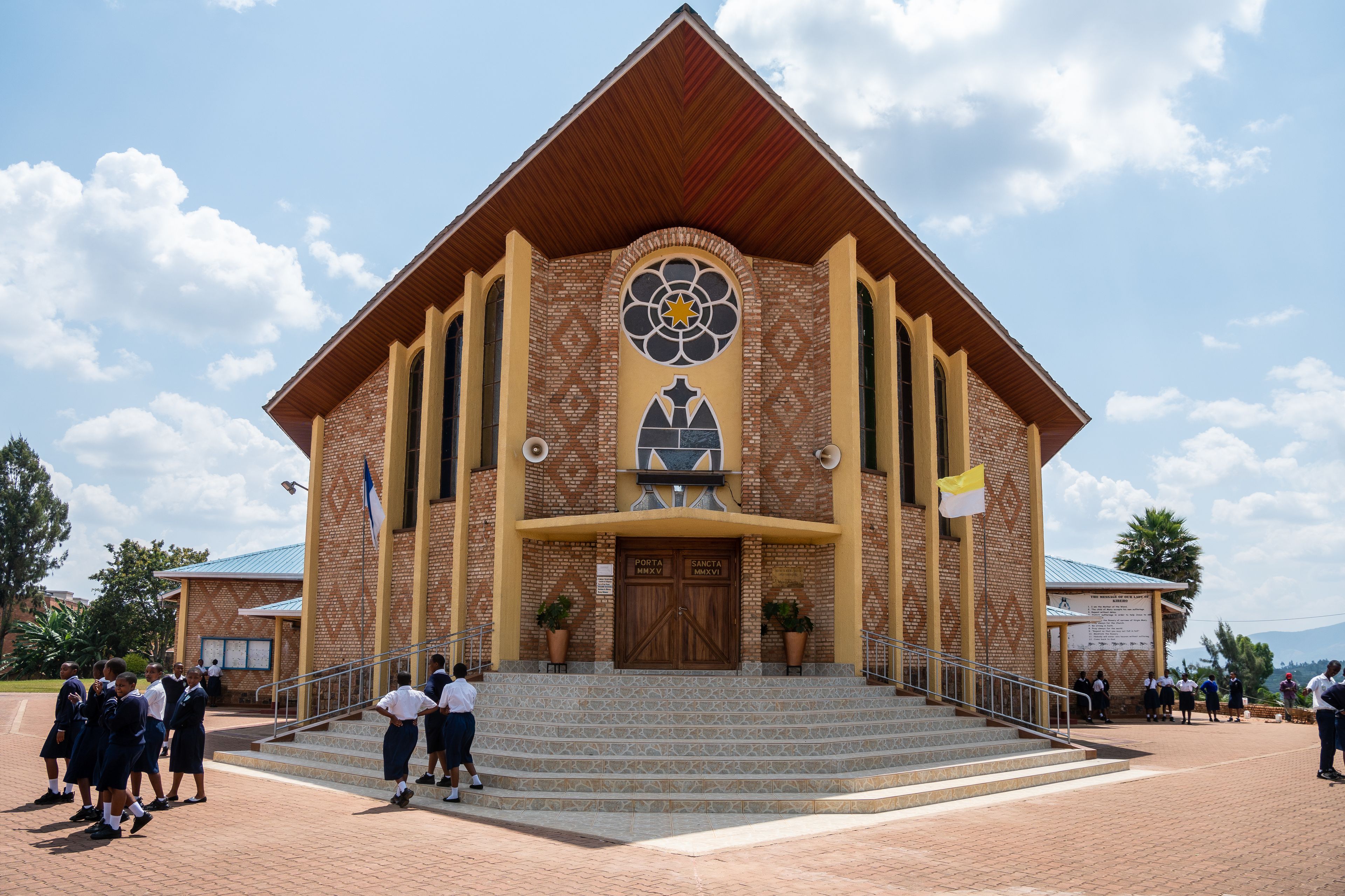A church with a large entrance, a bell tower, and a cross on the facade.
