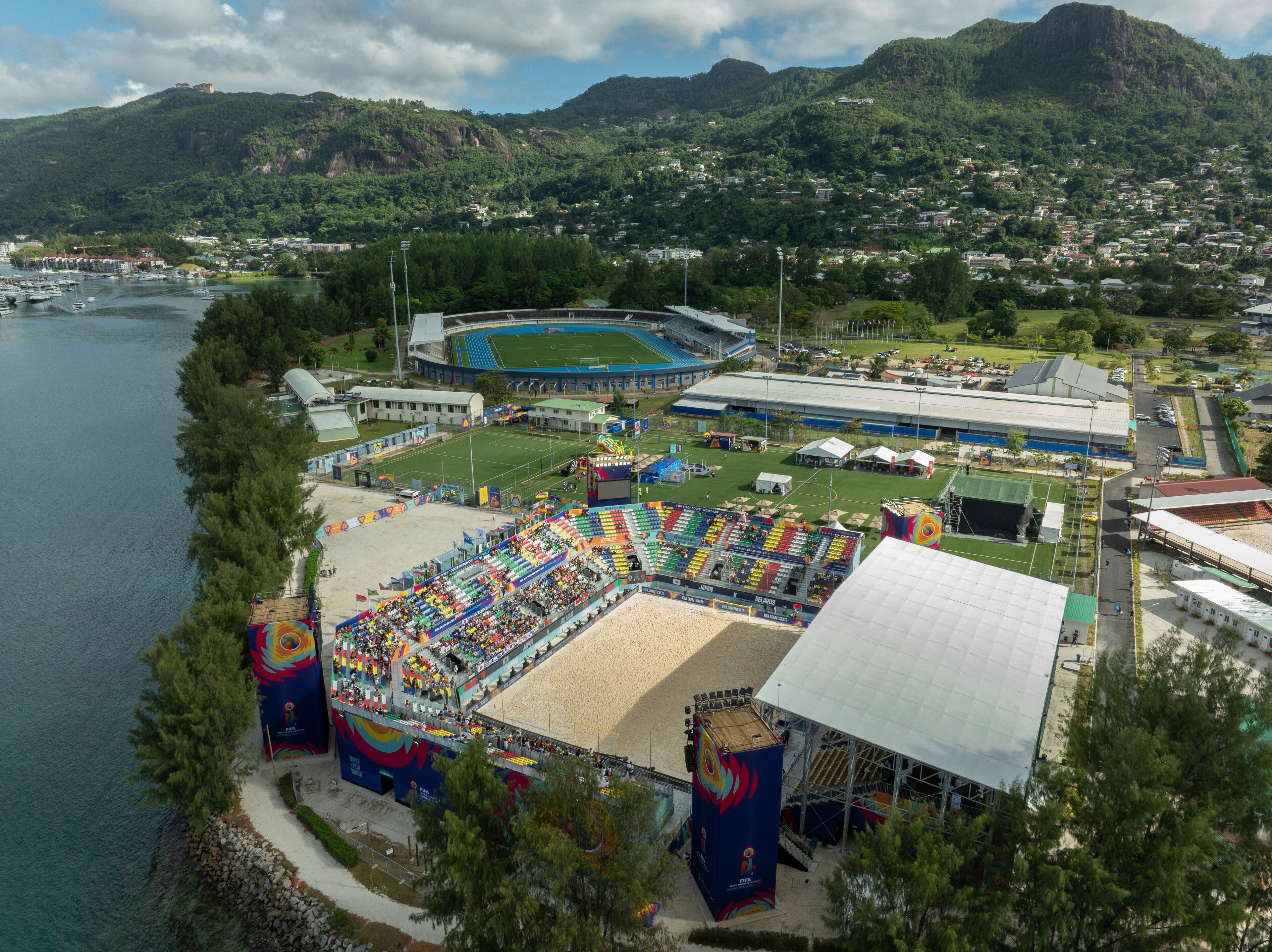 Mahé, Seychelles - 04 May 2025: Aerial view of vibrant stadium near the beach with lush mountains and tropical greenery, Roche Caiman, Mahe, Seychelles.