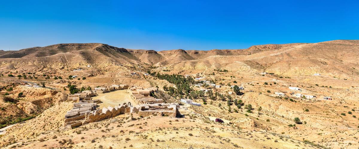 A desert landscape with a small settlement and ancient ruins.