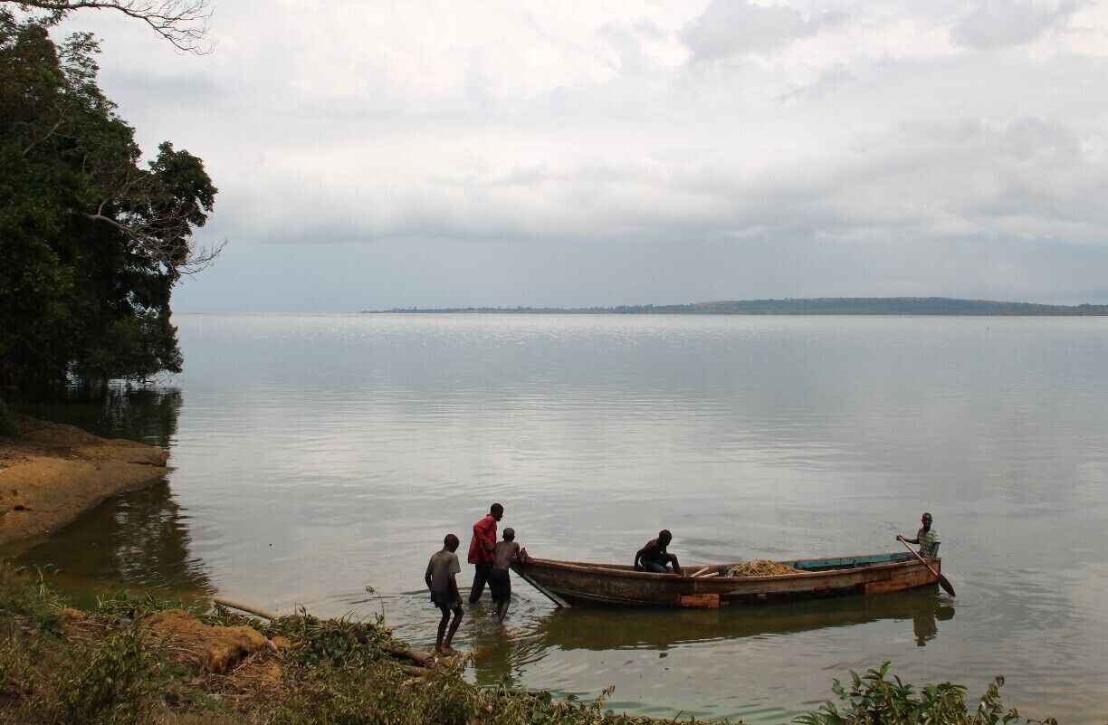 A calm lake with a small boat and people near the shore.