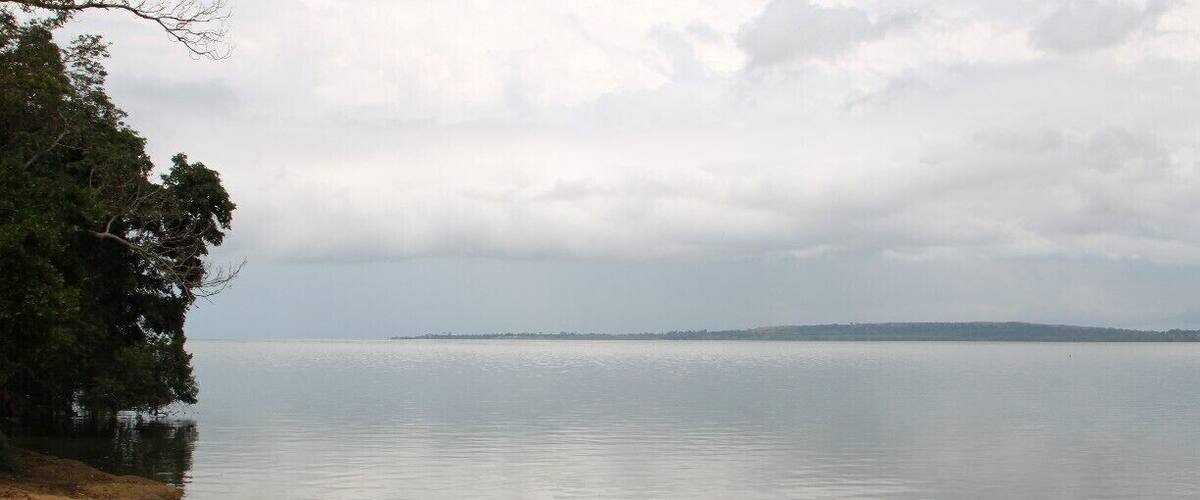 A calm lake with a small boat and people near the shore.