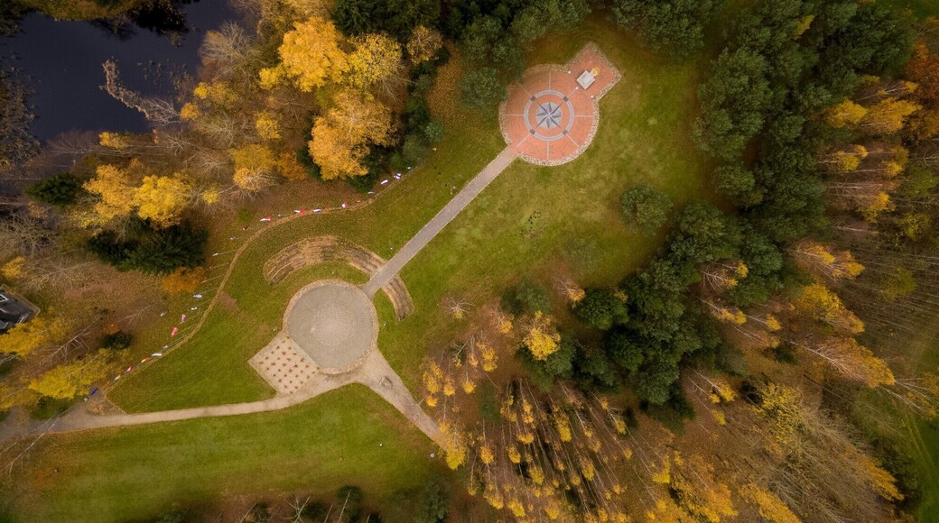 En vy över en park från ovan, med ett runt monument, en damm och träd runt omkring.