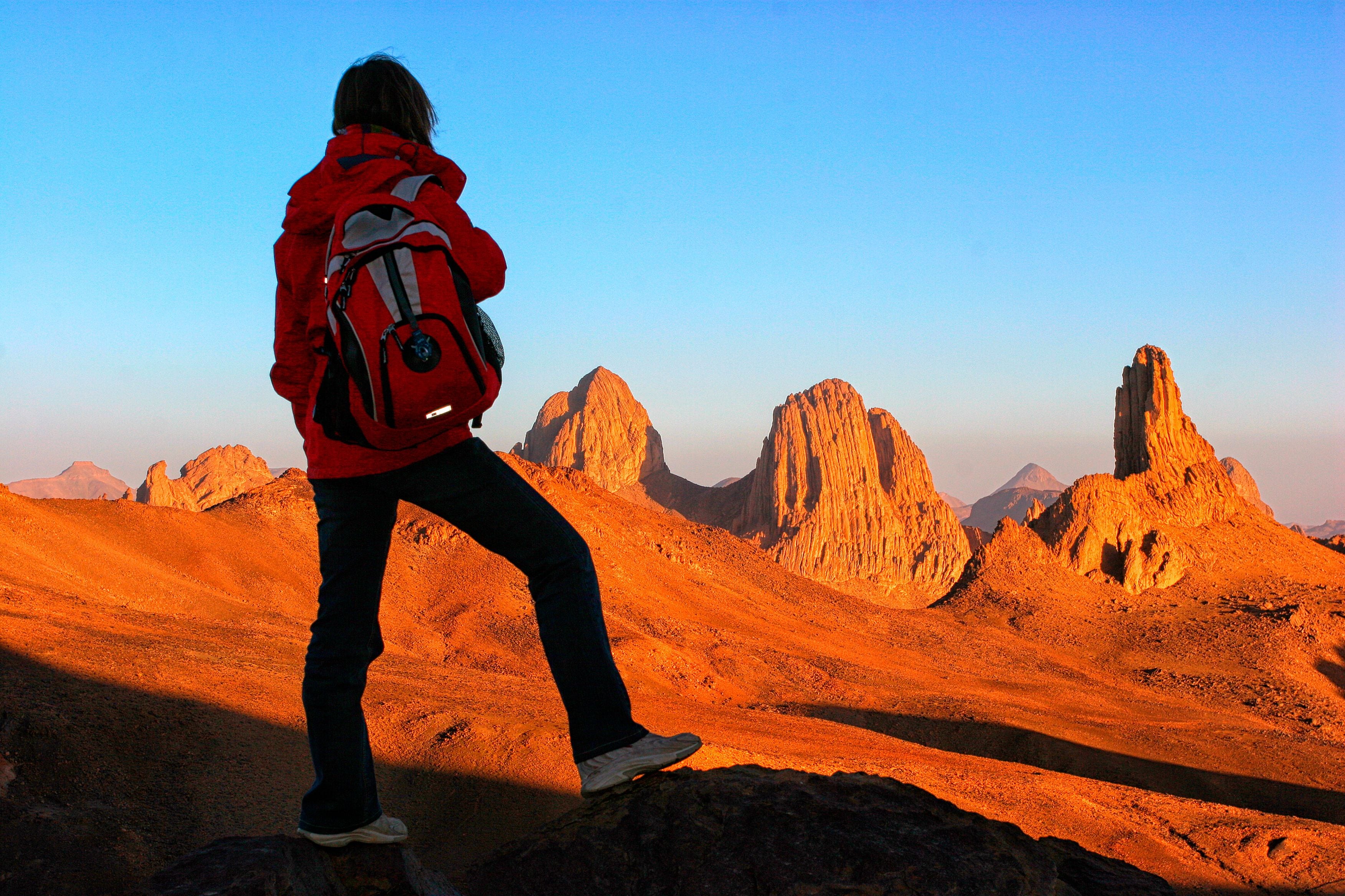 A person hiking in a desert landscape with rocky formations.