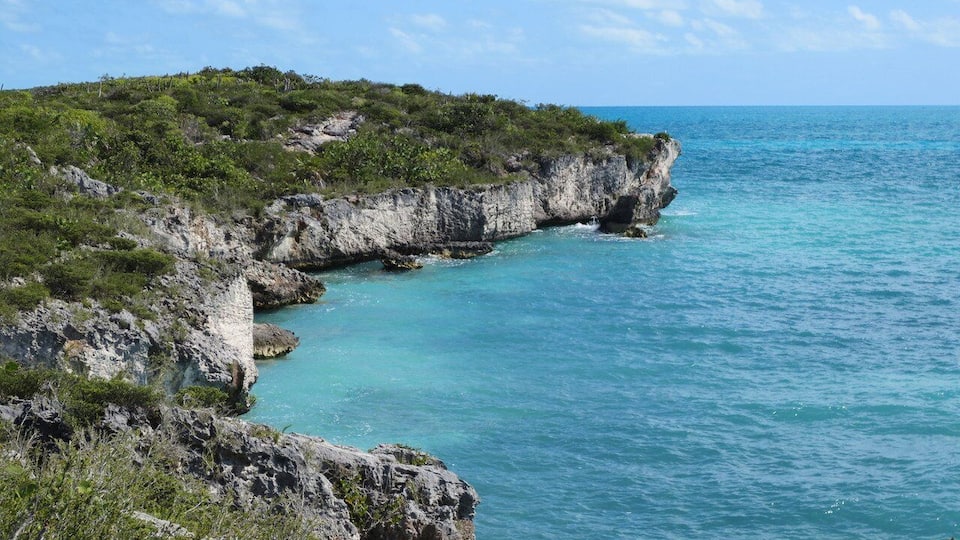 A coastal landscape with rocky cliffs and turquoise waters.