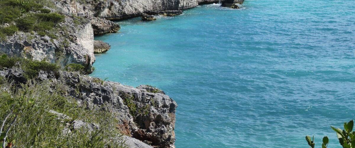 A coastal landscape with rocky cliffs and turquoise waters.