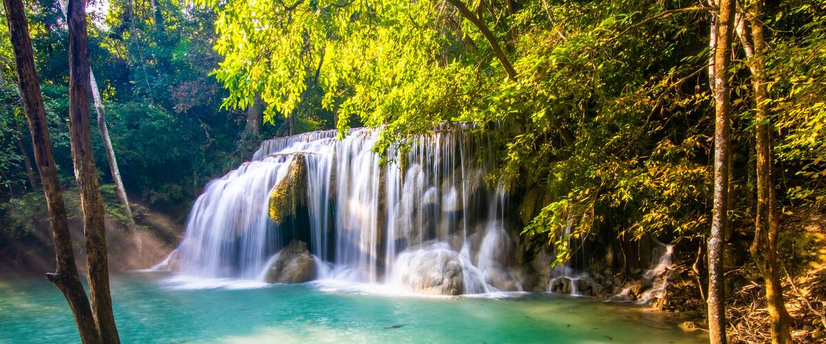 A waterfall cascading into a clear turquoise pool surrounded by lush greenery.