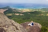 A woman sits and admires the coastal view from the top of Mount Nosoko in Ishigaki, Okinawa, Japan