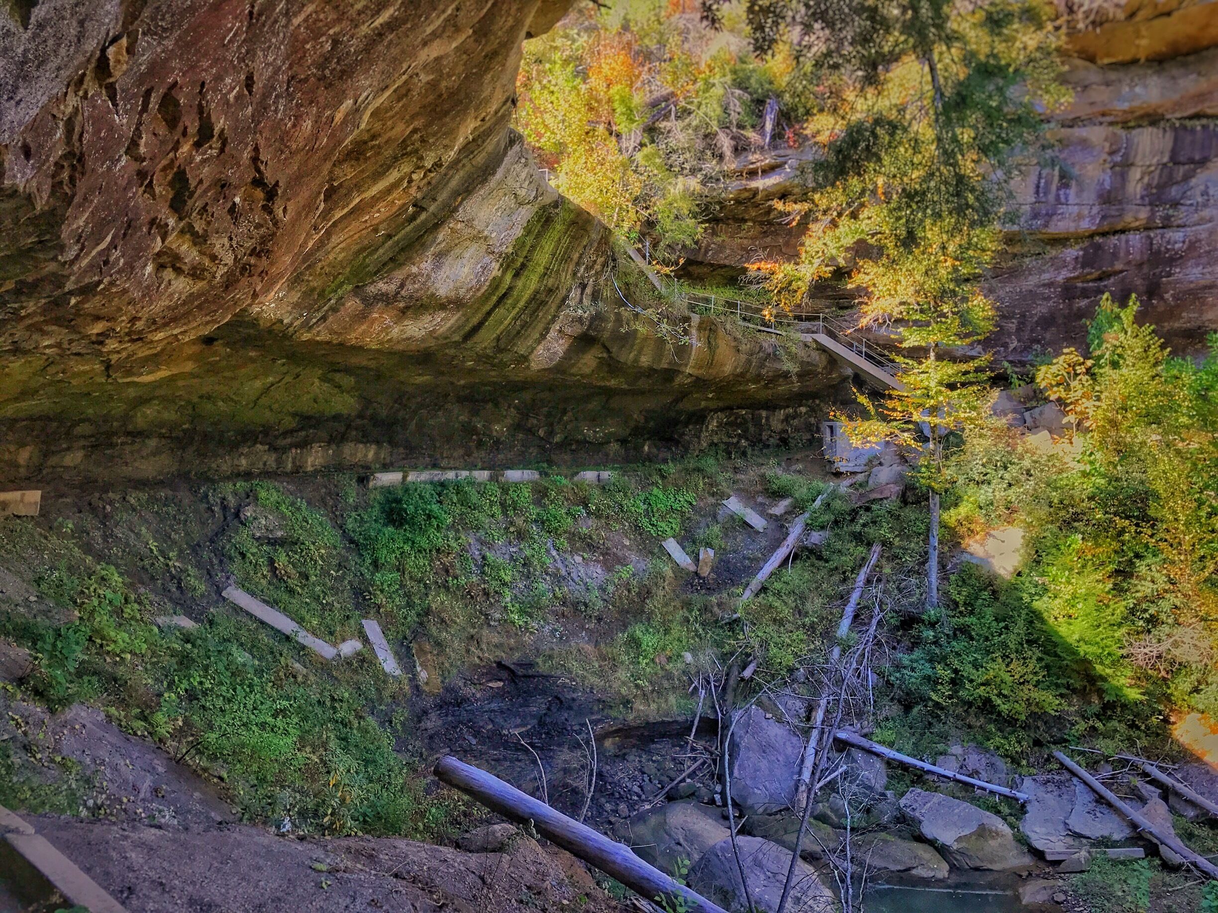      After climbing down slippery stair steps and through the bolder strewn gorge below, there's little doubt left about the naming of Broke Leg Falls. 
     Closed to the public for years, Menifee County reopened the Broke Leg Falls. Nearby Frenchburg on U.S. Route 460, Broke Leg Falls Park Bridge the 60 foot waterfall is nearly out of driving range from the major attractions of Natural Bridge State Park and Red River Gorge. Although the area draws little attention, it's well worth the extra drive. Some say this Kentucky waterfall setting earns the adjectives of stunning, and remarkable. 
     Stairs lead down from the parking area into the gorge and behind the waterfall. A small footbridge crosses over the creek below and leads to various viewpoints along the creekside. It's best to keep an eye on where you are stepping, rather than fixing your gaze on the fall. It would be a bad day if you were to join the members of the Broke Leg Falls gang. 


Normally there is a beautiful waterfall where you see the black streaks, but we're in a a drought, so just use your imagination. 
Taken on iPhone 7+