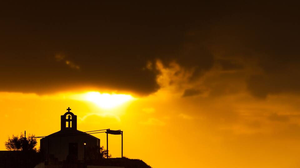 A church silhouette against a sunset sky.