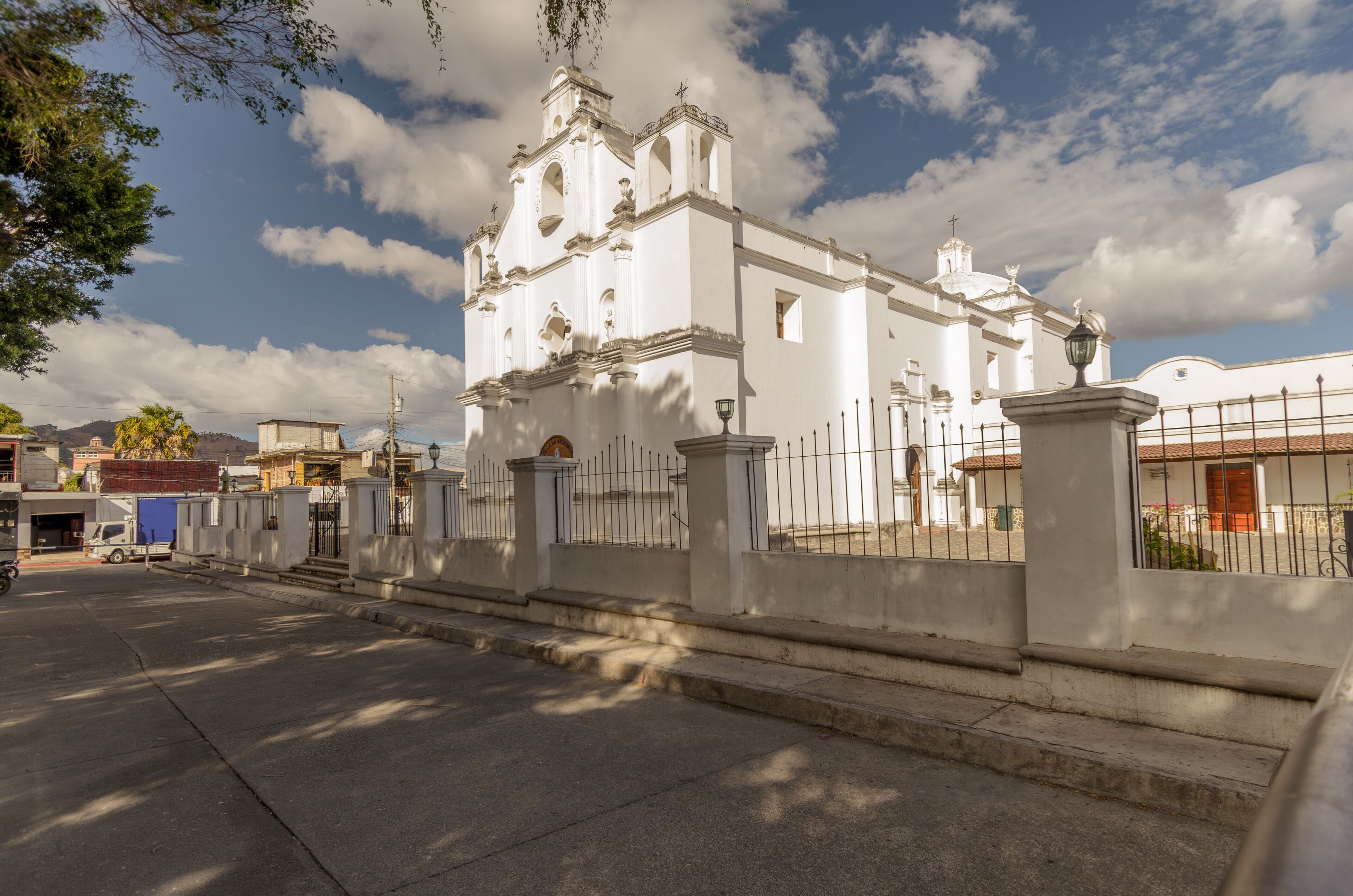 A white church with a bell tower and a fence in front.